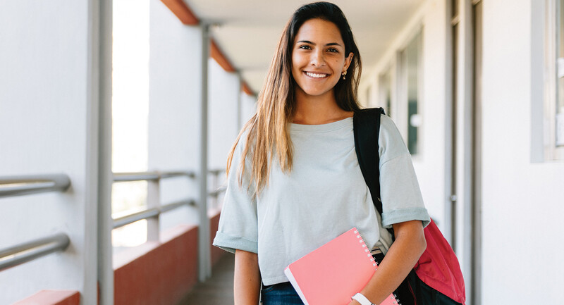 photo of a smiling teenager holding a notebook